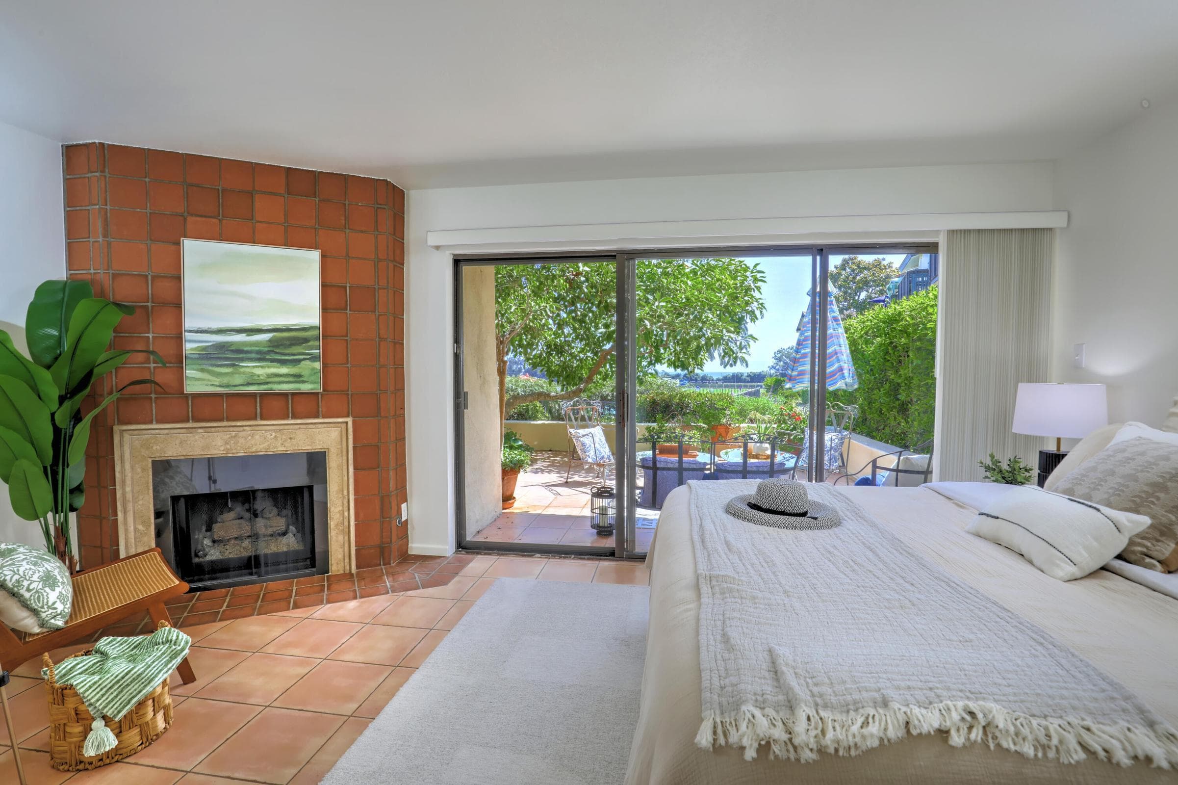 spacious primary bedroom with corner fireplace; sliders open to large terrace