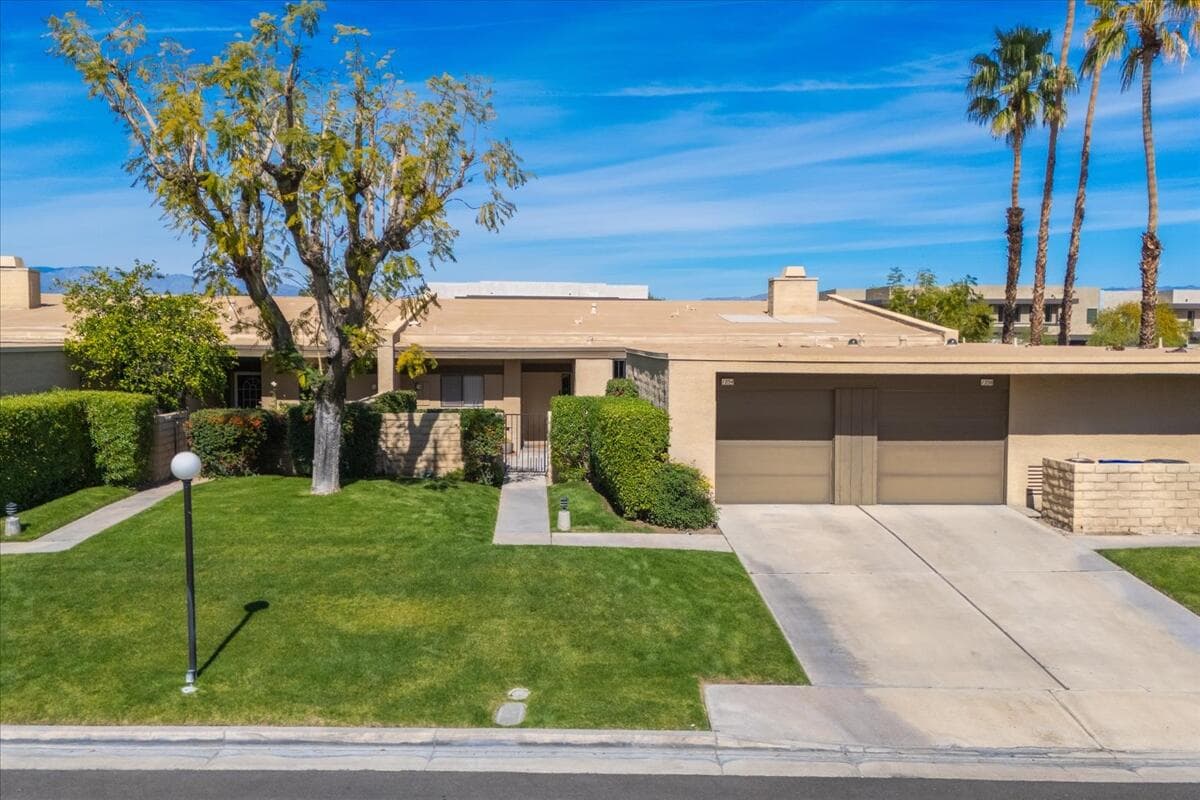 Classic Palm Springs curb appeal with manicured lawn, clean lines, and mountain skies setting the tone for easy desert living.