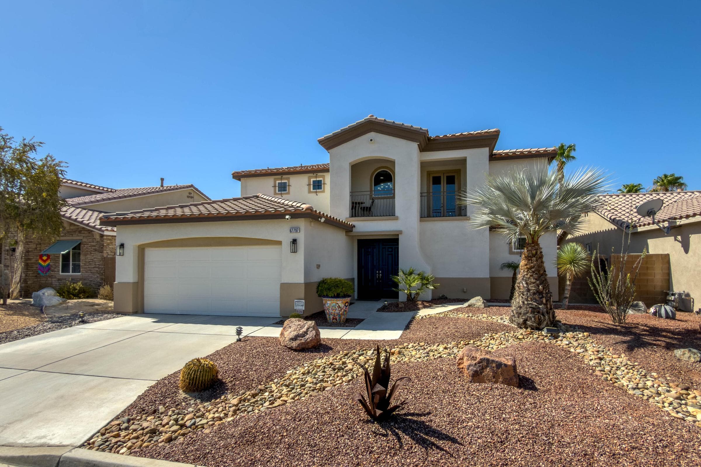 Front of property with lush desert landscaping.